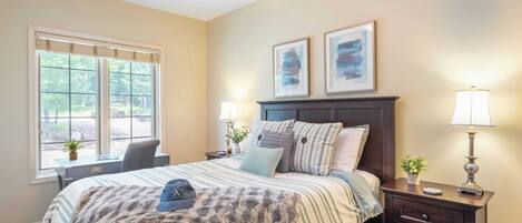 A bedroom with a bed, bedside tables, a desk, and a window.
