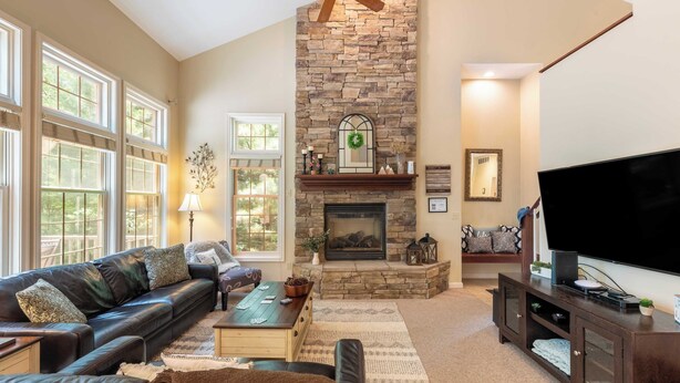 A living room with a stone fireplace, leather sofa, and a flat-screen TV.