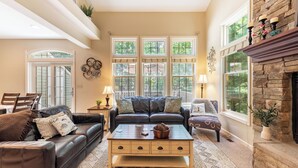 A living room with a fireplace, a sofa, a coffee table, and a dining area with chairs.