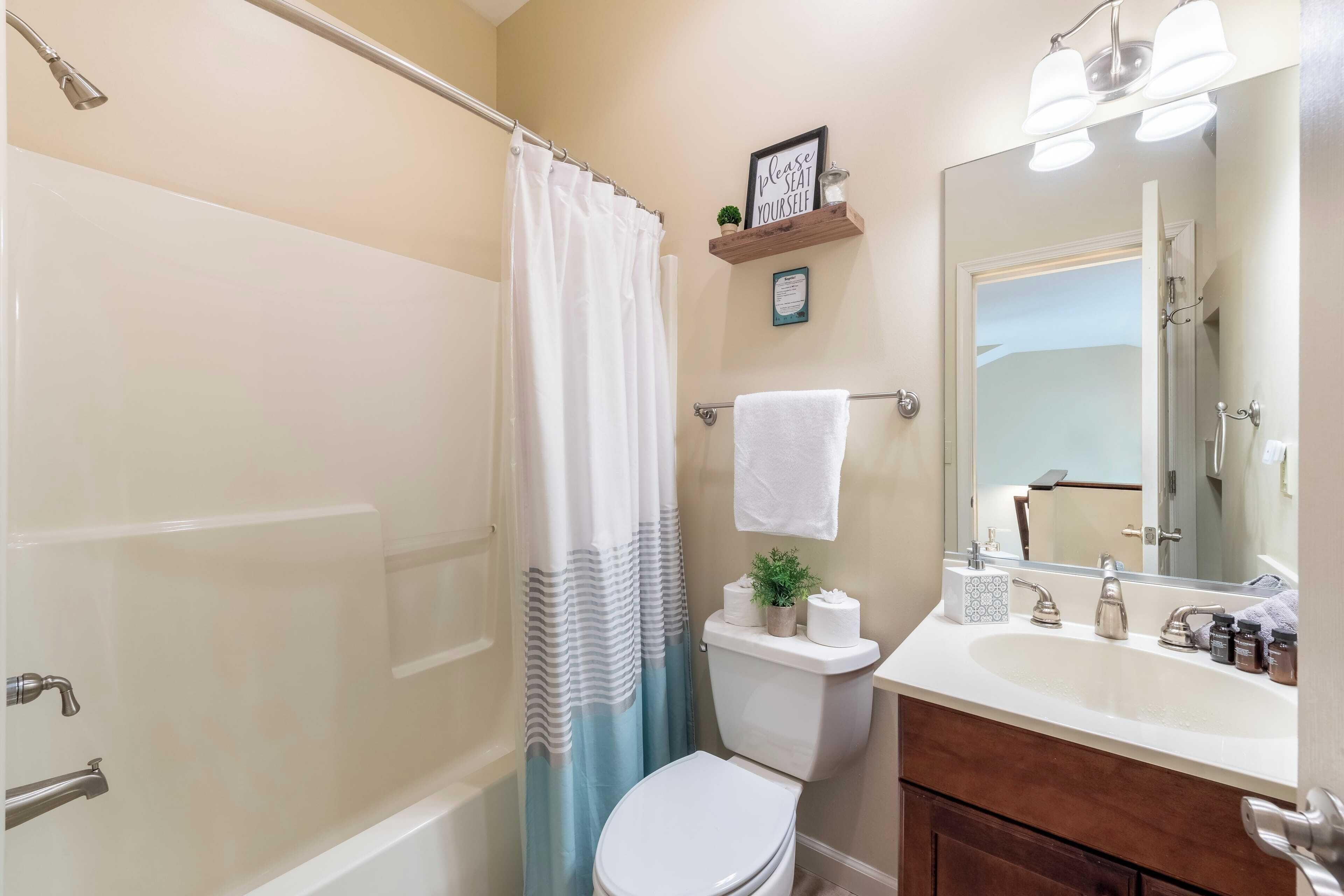 A bathroom with a bathtub, toilet, sink, and a shower curtain.