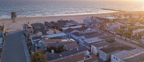 An aerial view of a coastal residential area with houses, a beach, and a clear sky.