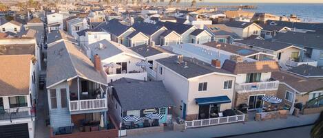 A coastal residential area with houses featuring balconies, some with outdoor seating and umbrellas.