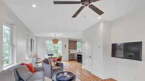 A spacious living room with a grey sofa, a coffee table, and a ceiling fan.