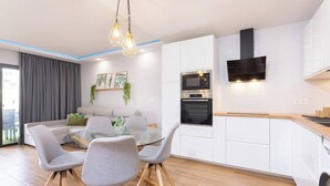 A modern kitchen with white cabinets, a built-in oven, and a black range hood. - Home2Book Stylish Oasis Pool&Terrace Golf del Sur (Arona)