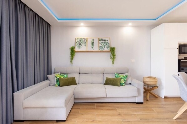 A modern living room with a sectional sofa, a small round table, and a wall-mounted plant display.
