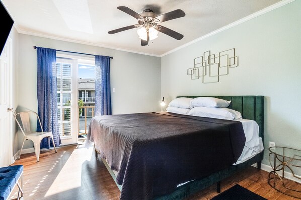 A bedroom with a bed, a ceiling fan, a chair, a nightstand, and a view of the outside. - LALALAND -2 master suites, king bed,  comfort & location “No chores” at checkout (Lafayette)
