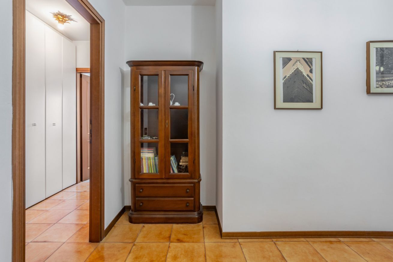 Ein Flur mit einem Holzschrank, einer Tür und zwei gerahmten Bildern an der Wand.