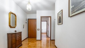 A hallway with a wooden cabinet, a mirror, and a door leading to another room. - GuestHost - Spacious and bright 130 sqm apartment, perfect for 4 people, located on the second floor of a building WITHOUT a lift (stairs to access it).The apartment is located 4.1 km from the center of Lucca: in just 13 minutes by bus you can reach the  (Lucca)