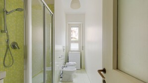 Een badkamer met douche, toilet en bidet.