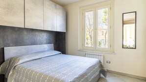 A bedroom with a bed, a window, and a radiator.