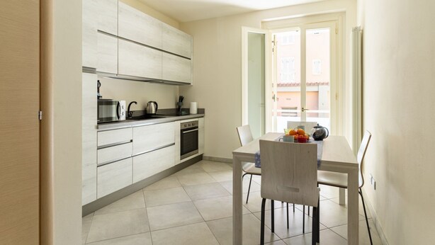 A modern kitchen with a dining area, featuring a window with a view of buildings.
