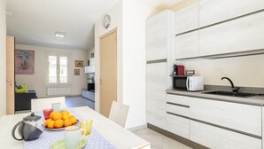 A modern kitchen with white cabinets, a microwave, and a sink.