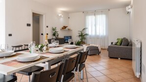 A modern living room with a dining area, a grey sofa, and a television. - Terraced villa Golden Lake 1 - a few steps from the lake (Dervio)