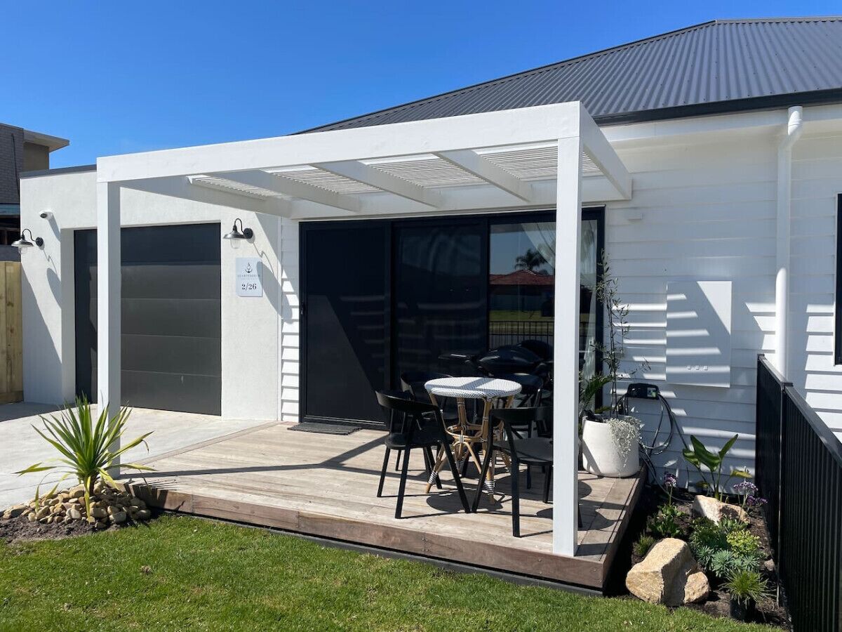 A modern house with a covered patio, outdoor seating, and a well-maintained garden.