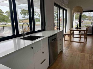 Una cucina moderna con un'ampia finestra, una lavastoviglie e un'area pranzo con tavolo e sedie.