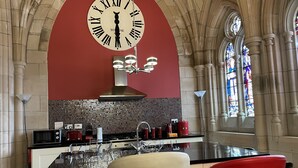Une cuisine avec une grande horloge, un mur rouge et un vitrail.