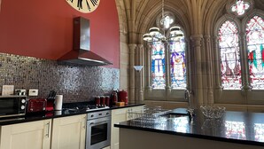 Une cuisine dotée d’une grande horloge, d’une cuisinière moderne et d’un vitrail.