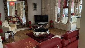 Un salon avec un canapé rouge, un téléviseur et un grand miroir.