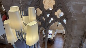 Un lustre à plusieurs lampes, un mur en pierre orné d’un motif d’arbre sculpté et un coin repas avec une table et des chaises.