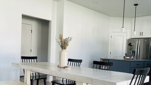 A modern kitchen with white cabinets, a large island, and a dining area with a bench and chairs. - Hot Tub - Cozy Retreat in Springville (Springville)