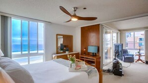 Ein Hotelzimmer mit einem Bett, einem Schreibtisch mit Lampe, einem Fernseher und Blick auf den Ozean.