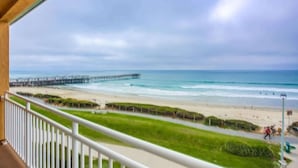 Ein Balkon mit Blick auf einen Strand, eine Mole und einen klaren Himmel.