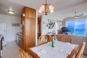 A dining area with a table set for two, a bottle of champagne, and a television in the background. - New Low Rates Len and Marys Beach Front 2 BD Condo (San Diego)