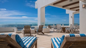 Enjoy the ocean view from this rooftop terrace, featuring comfortable lounge chairs and tables.