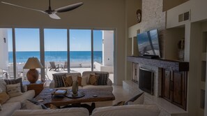 Enjoy the ocean view from the large window in this living room, featuring a sofa, coffee table, and fireplace.