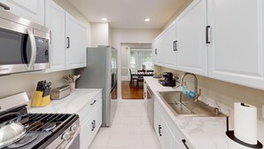 A modern kitchen with white cabinets, stainless steel appliances, and a central island with a sink and countertop.