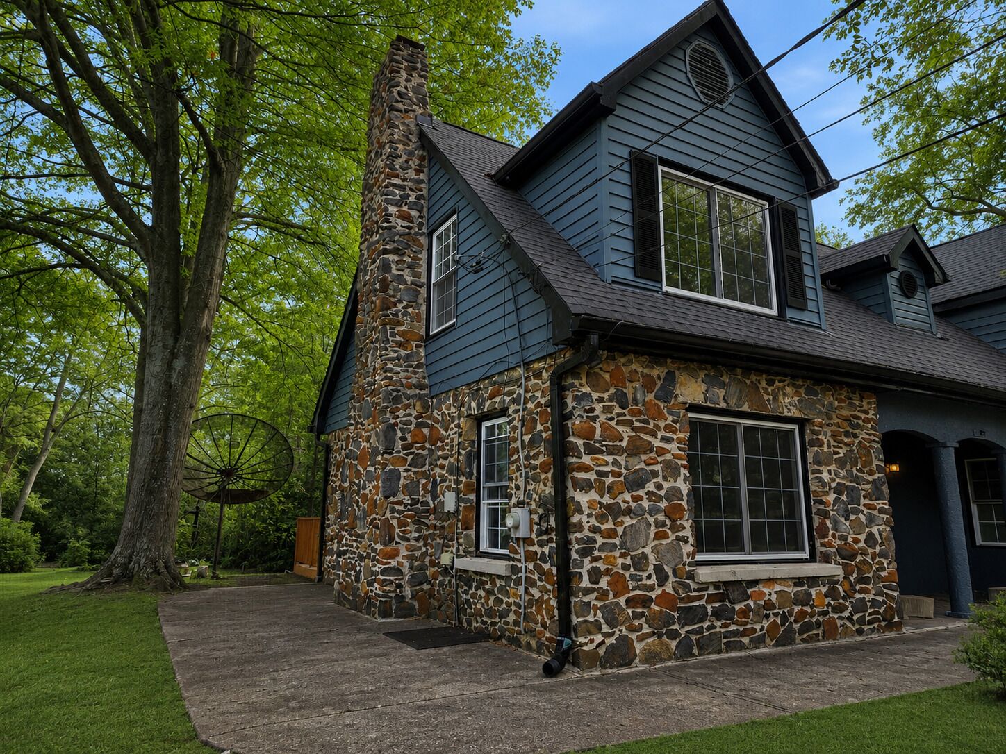 A two-story stone house with a steep gable roof and a chimney.