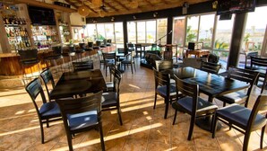 A restaurant with outdoor seating, a bar area, and large windows.