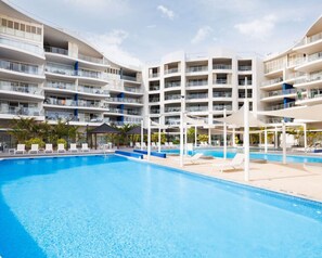 Un hôtel moderne doté d’une grande piscine, de nombreux balcons et d’espaces extérieurs aménagés pour se détendre.