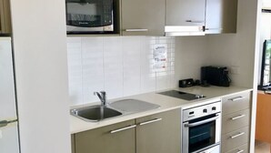 A modern kitchen with a built-in microwave, a sink, a stove, and a coffee maker. - 180˚ Water View Apartment - Simply Stunning (Urangan)