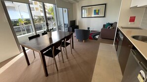 A modern kitchen with a dining area, large windows, and a view of the outdoors.
