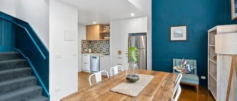 A modern kitchen with white cabinets, a stainless steel refrigerator, and a patterned backsplash.