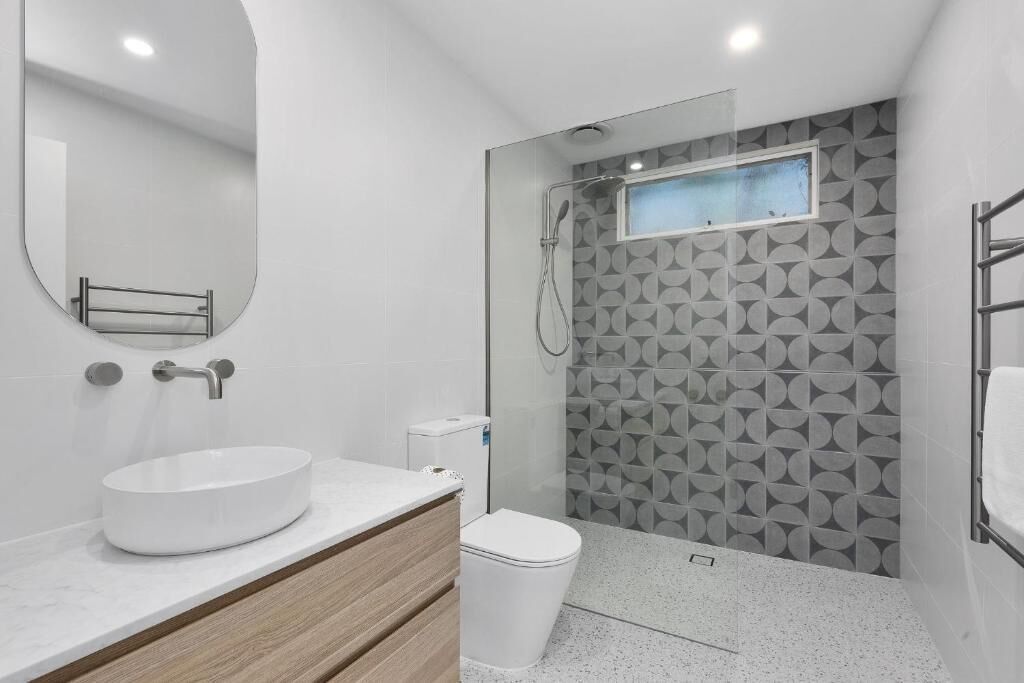 A modern bathroom with a round sink, toilet, and shower.