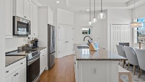 A modern kitchen with white cabinetry, stainless steel appliances, and a granite countertop. - 155 Inn-2-Blue: Poolside Fun & Beach Walks Await! (Fort Myers Beach)