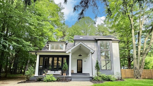 A two-story house with a porch, large windows, and a well-maintained lawn.