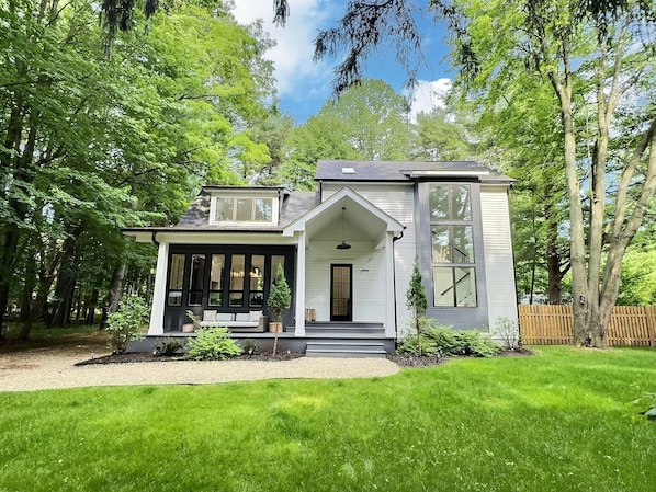 A two-story house with a porch, large windows, and a well-maintained lawn.