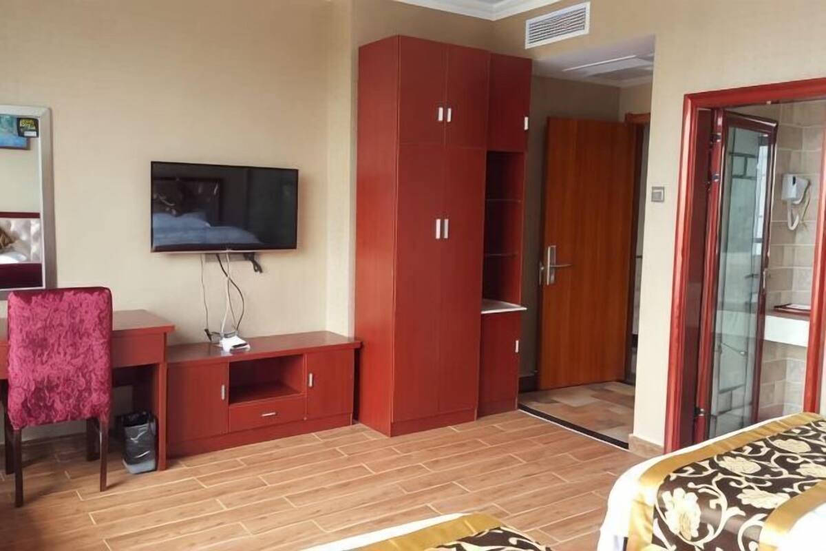 Une chambre d’hôtel équipée d’une télévision, d’une armoire rouge, d’un bureau et d’un lit.