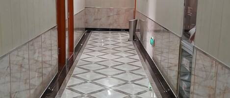 A corridor with a tiled floor and a trash bin.