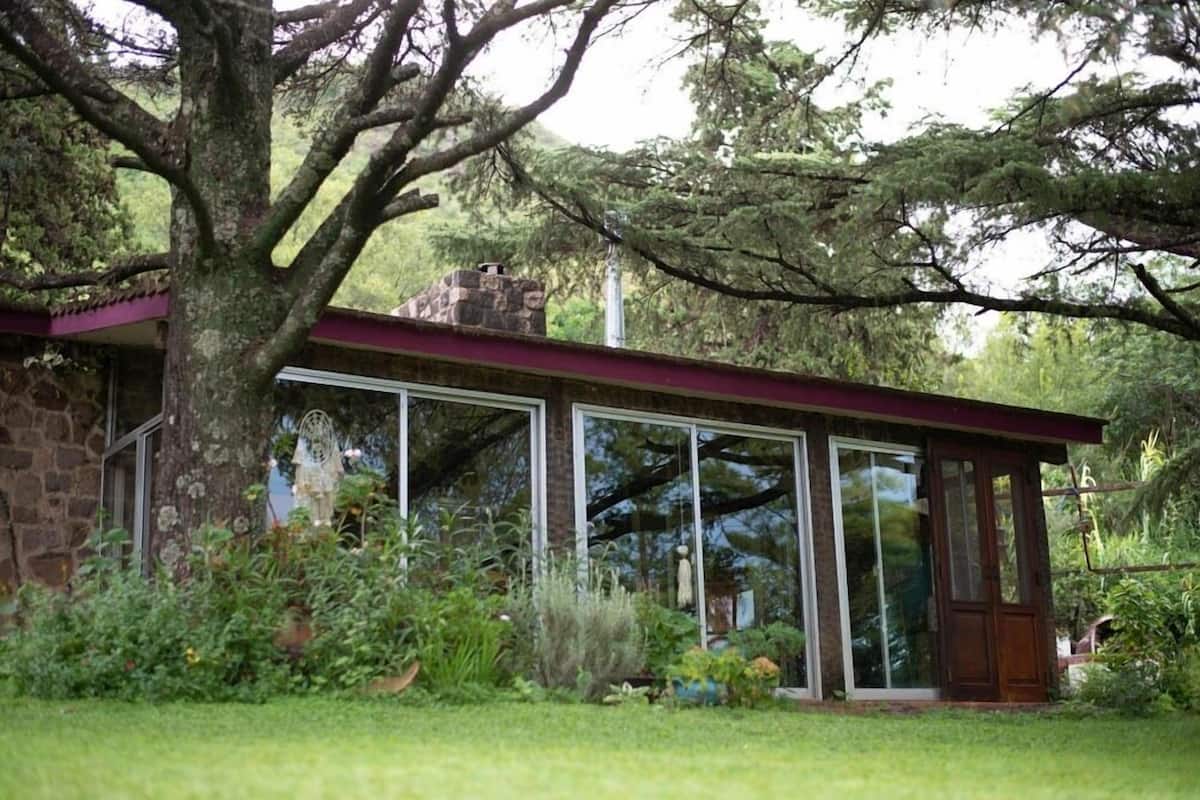 Une maison avec une façade en pierre, de grandes fenêtres en verre et un toit rouge.