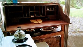 A compact kitchen with a gas stove, a kettle, and a small countertop.