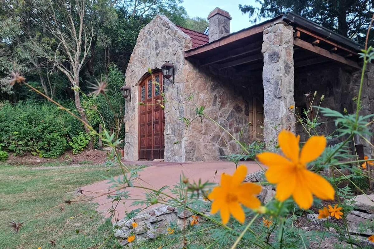 Un bâtiment en pierre avec une porte en bois et une cheminée.