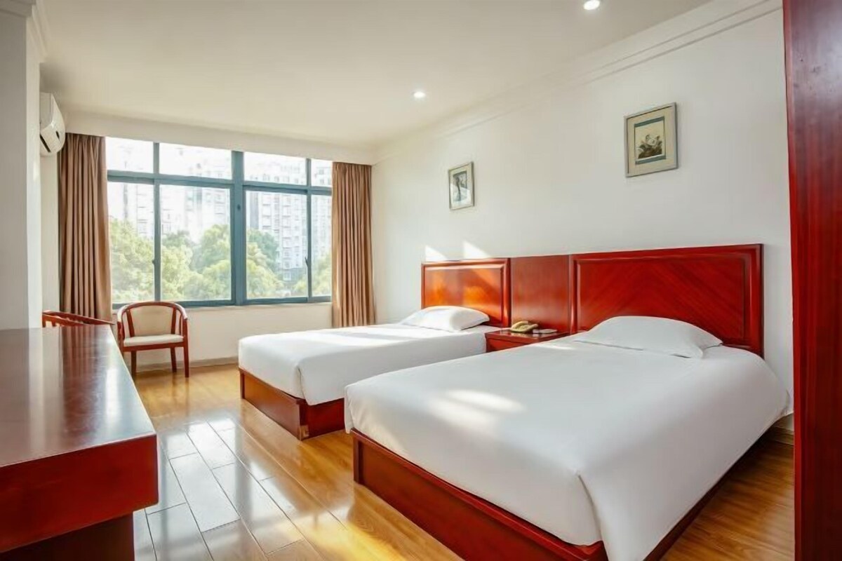 A hotel room with two beds, a desk, and a chair.