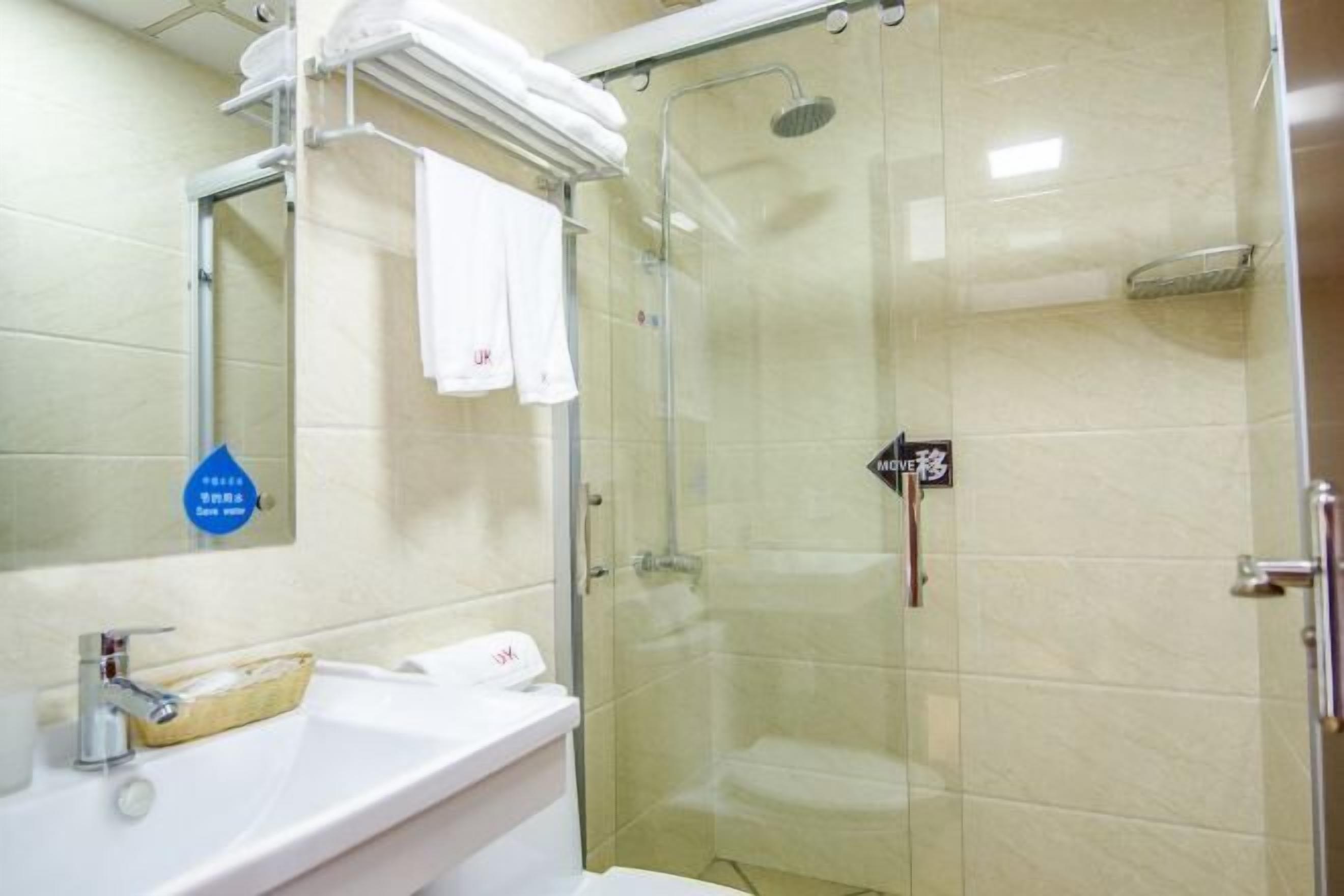 A bathroom with a glass-enclosed shower, a sink with a mirror, and a towel rack.