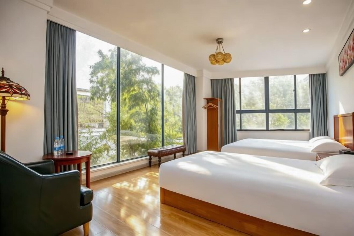 A hotel room with a large bed, a desk, and a view of the outdoors.