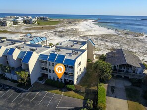 Un hôtel situé en bord de mer, composé de plusieurs bâtiments, doté d’un parking et donnant sur une plage de sable.