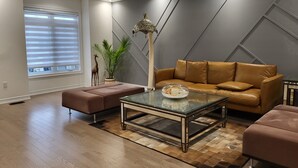 Ein modernes Wohnzimmer mit einem braunen Ledersofa, einem Glastisch und Holzboden.